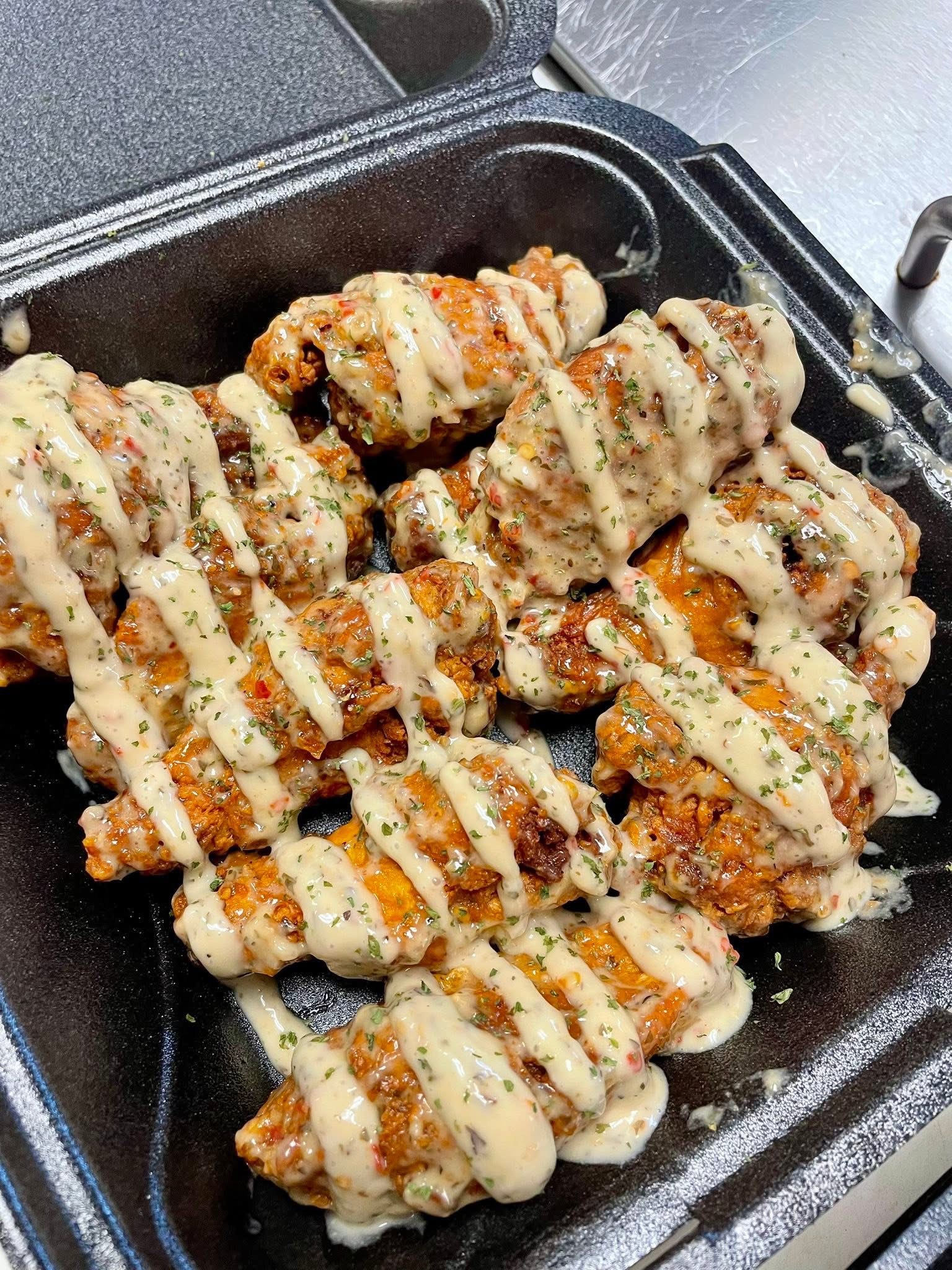A ten piece order of wings under a heavy drizzle of sauce