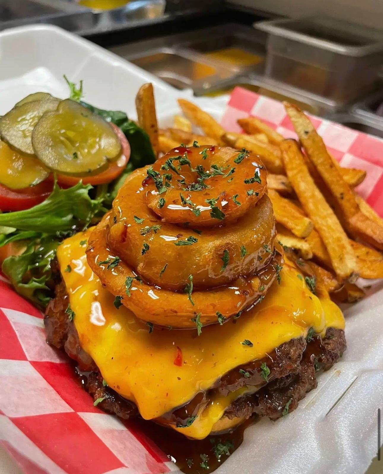 Rodeo Burger: a beef patty under melted cheese with stacked onion rings and a barbecue glaze, fries alongside